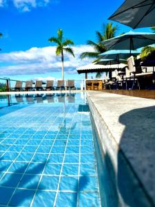 uma piscina com cadeiras e guarda-sóis num resort em Barra Grande Exclusive Residence em Barra Grande