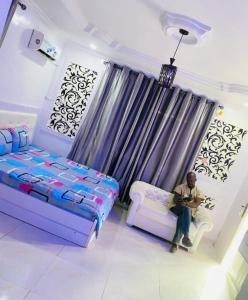 Un uomo seduto su un divano in una stanza di White Emirates Hotel and Apartment a Lagos