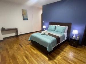 a bedroom with a bed with blue walls and wooden floors at Hermoso Departamento En La Mejor Zona De Cochabamba in Cochabamba