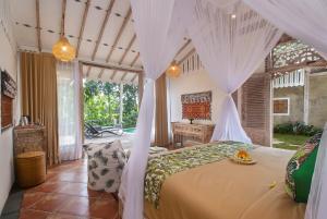 sypialnia z łóżkiem z baldachimem i biurkiem w obiekcie Sacred Beji by Pramana Villas w mieście Payangan