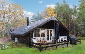 una cabaña con techo negro en el bosque en Cozy Home In Oksbl With Kitchen, en Oksbøl