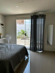 sypialnia z łóżkiem i przesuwnymi szklanymi drzwiami w obiekcie Tumbes Zorritos Bocapan Casa con piscina 3 dormitorios w mieście Bocapán