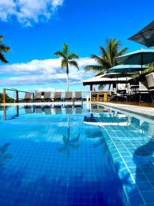 uma piscina com cadeiras e guarda-sóis numa praia em Barra Grande Exclusive Residence em Barra Grande