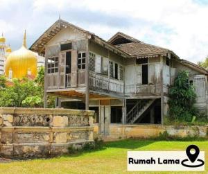 una vieja casa en Rumania con una mezquita en el fondo en Homestay Eco Rengas Jaya, en Padang Rengas