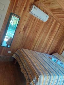 1 dormitorio con 1 cama en una habitación con ventana en Cabañas El Okaso del Sol, en Santa Cruz