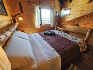 um quarto com uma cama num chalé de madeira em Cabañas Alechen em El Calafate