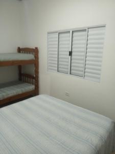 a bedroom with a bed and a window with shutters at Casa mirante Bela Vista in Guarujá