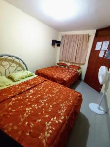 a bedroom with two beds and a fan at Hostal Cix - Chiclayo in Chiclayo