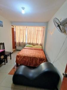 a bedroom with a bed and a black ottoman at Hostal Cix - Chiclayo in Chiclayo