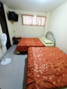 a bedroom with two beds and a fan and a window at Hostal Cix - Chiclayo in Chiclayo