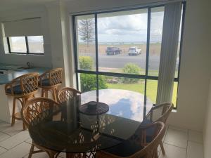 d'une salle à manger avec une table, des chaises et une fenêtre. dans l'établissement Hi Surf Unit 2, 92 Head Street, Forster, à Forster