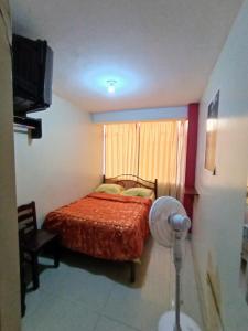 a bedroom with a bed and a window with a fan at Hostal Cix - Chiclayo in Chiclayo