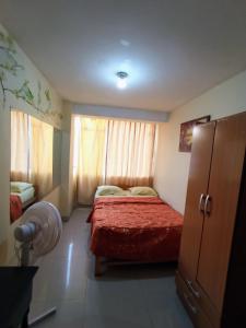 a bedroom with a bed with a red blanket and a window at Hostal Cix - Chiclayo in Chiclayo