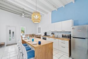 una cocina con armarios blancos y una mesa con sillas azules en Beautiful and Spacious Mediterranean Style Villa on Palm Beach en Palm-Eagle Beach