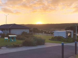a sunset over a house with a picnic table at Southern Ocean Motor Inn in Port Campbell