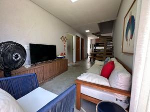 a living room with a couch and a flat screen tv at Flat Aconchegante a 200m do Mar - Praia Marceneiro in Passo de Camarajibe