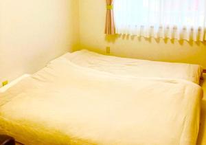 a white bed in a room with a window at ゲストハウス西金沢Smile&smile in Kanazawa