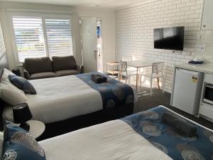 a hotel room with two beds and a television at Southern Ocean Motor Inn in Port Campbell