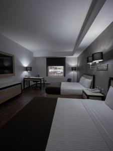 a hotel room with two beds and a television at Fato Hotel in Querétaro
