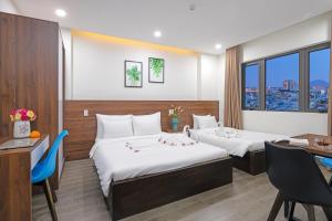 a hotel room with two beds and a desk at TIDITEL Hotel and Apartment in Da Nang