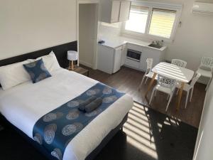 um quarto com uma cama e uma cozinha com uma mesa em Southern Ocean Motor Inn em Port Campbell