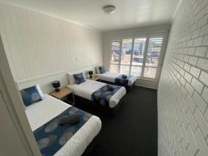 a room with three beds and a window at Southern Ocean Motor Inn in Port Campbell