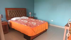 a bedroom with a bed with an orange bedspread at BUENDIA HOTEL in Pueblo Viejo