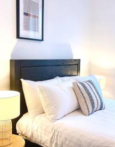 una cama con almohadas blancas encima en Luxury Hobart City Fringe Home en Hobart