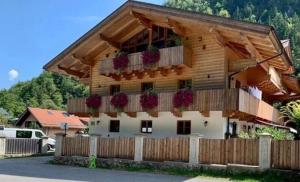 a wooden house with a balcony with flowers on it at Ferienwohnungen Kieferbachtal in Kiefersfelden