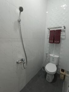 a bathroom with a shower with a toilet and towels at The Cabin Hotel Sumberan in Yogyakarta