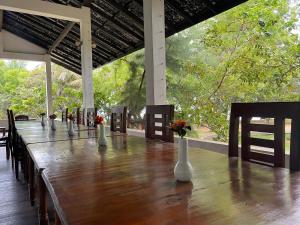 una larga mesa de madera con jarrones blancos. en Hotel Neithal Batticaloa, en Batticaloa