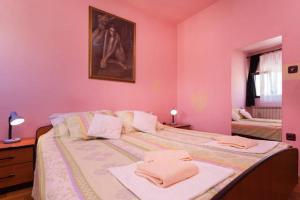 ein rosafarbenes Schlafzimmer mit einem großen Bett mit Handtüchern darauf in der Unterkunft Apartment Ingrid in Pula