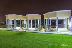a large white building with a green lawn at night at Bella Ella Hotel & Event Center in Kasoa