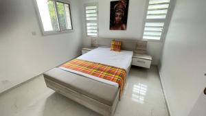een kleine slaapkamer met een bed en 2 ramen bij LE MANGO 'Lodge in Saint-François