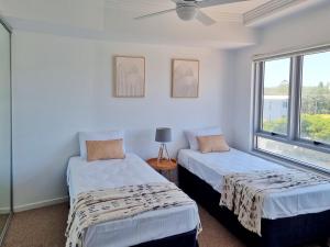 two beds in a room with a window at Pumicestone Blue Resort in Caloundra