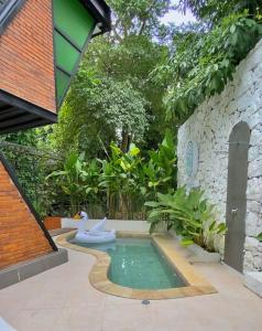 a swimming pool with a toilet in a garden at Sampai Villa Ruang Tepi in Yogyakarta