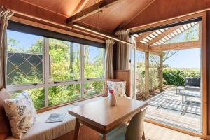 a living room with a table and a large window at The Shed Guest House in Mount Maunganui