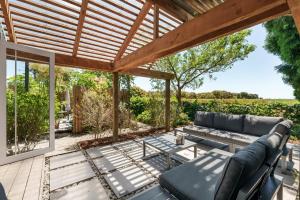 a patio with a couch and a table at The Shed Guest House in Mount Maunganui