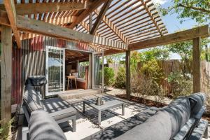 a patio with a couch and a wooden pergola at The Shed Guest House in Mount Maunganui