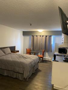 1 dormitorio con 1 cama y escritorio con TV en Nechako Valley Inn en Vanderhoof