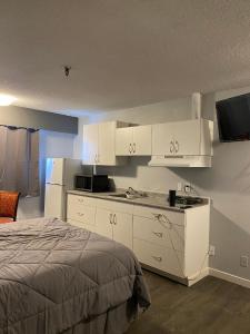 a bedroom with a bed and white cabinets and a television at Nechako Valley Inn in Vanderhoof