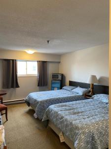 a hotel room with two beds and a window at Nechako Valley Inn in Vanderhoof
