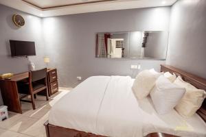 a bedroom with a bed and a desk and a television at Bella Ella Hotel & Event Center in Kasoa