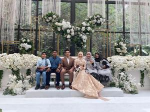 a group of people sitting on a bench at a wedding at Wan Homestay in Sungai Petani