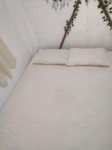 a white bed with two pillows on it at Beach Front Calatagan Apartelle in Calatagan