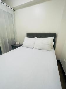 1 cama con sábanas blancas y almohadas en una habitación en 1 Bedroom with Balcony, en Manila