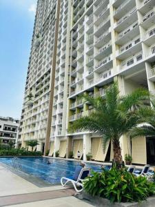 un grand immeuble avec un palmier et une piscine dans l'établissement 1 Bedroom with Balcony, à Manille