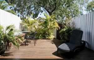 a patio with chairs and a table on a wooden deck at Wala Villa in Noosaville