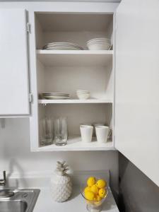 a kitchen cabinet filled with dishes and a bowl of fruit at Hostel Beds & Sheets FLL AIRPORT in Dania Beach