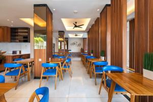 a restaurant with wooden tables and blue chairs at Boss Legian Hotel Powered by Archipelago in Legian
